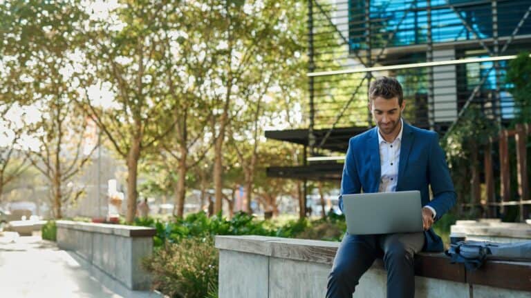 man working outside on his laptop by office