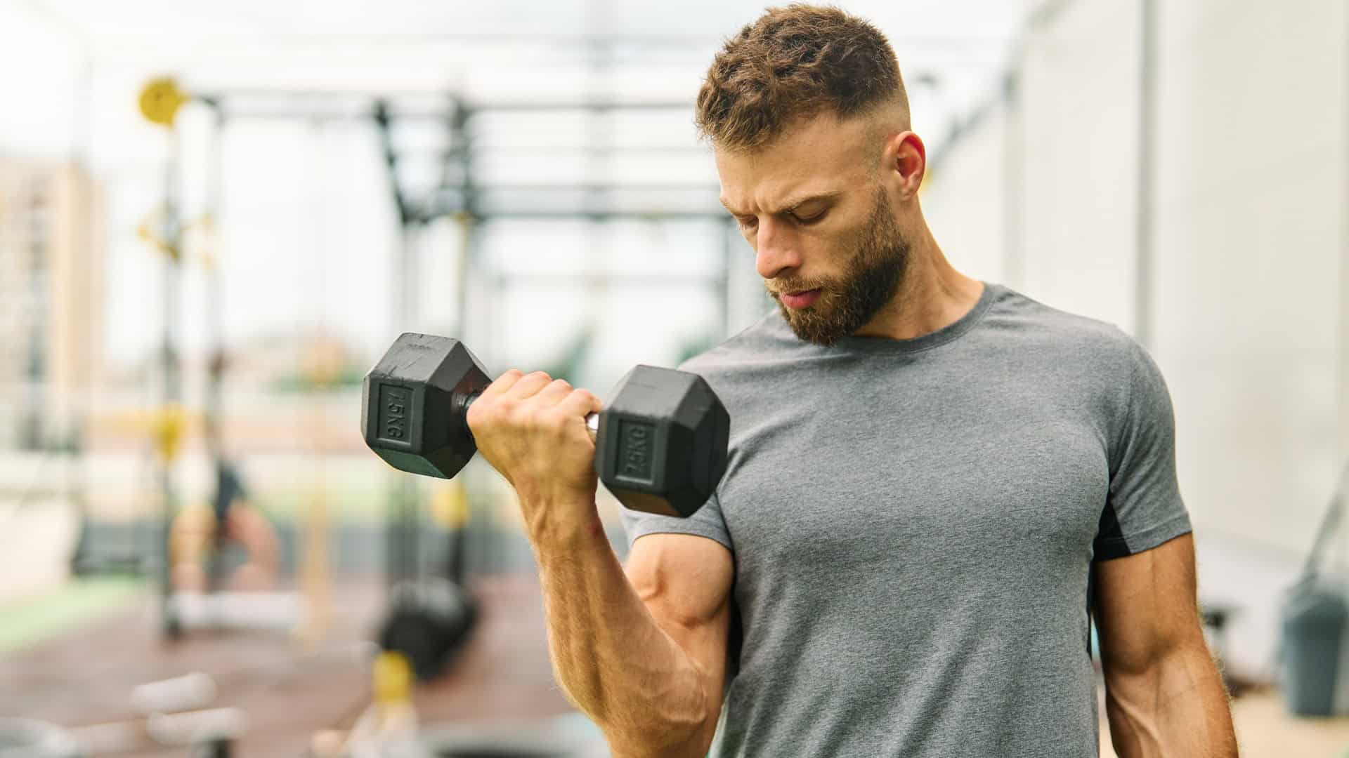 man lifting dumbbells in a gym