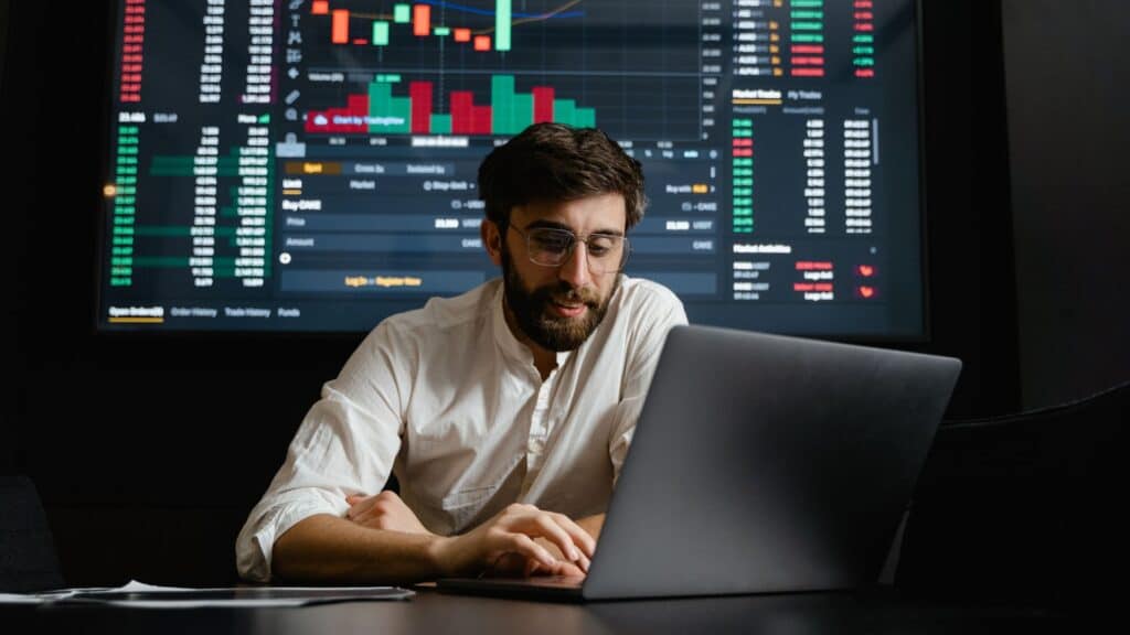 Man working on laptop with chart in the background.