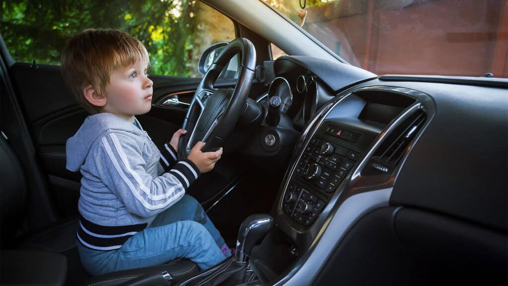 A young boy is driving a car.