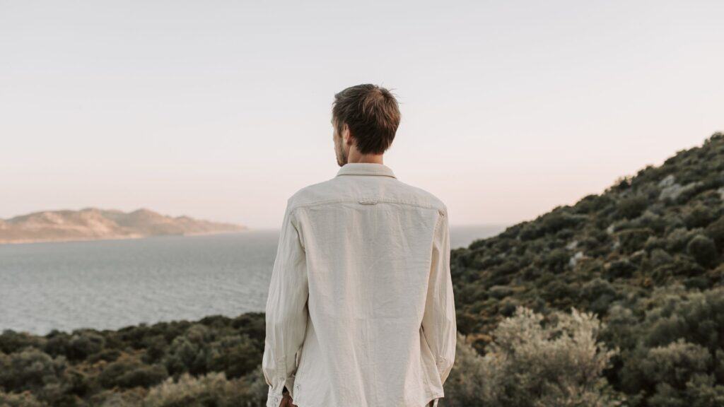 Man overlooking ocean and hills, outdoor lifestyle, peaceful nature scene.