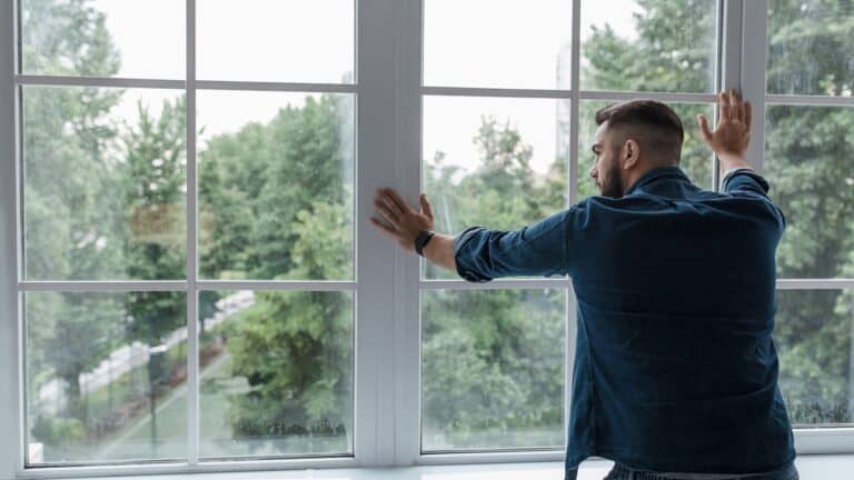 Man looking out of the window, thinking and enjoying fresh outdoor view.