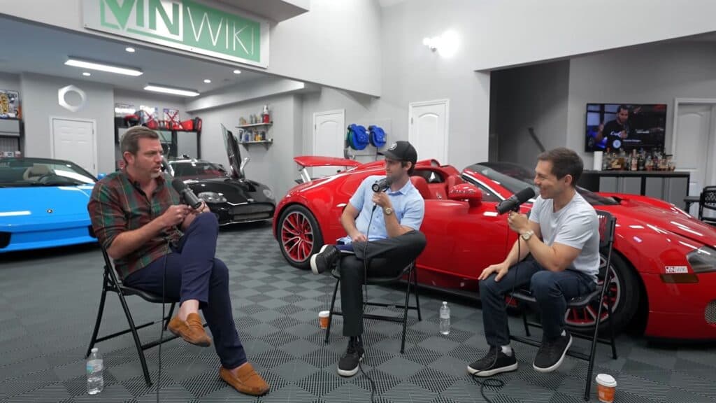 Three men conducting a podcast interview sitting in a garage of luxury sports cars