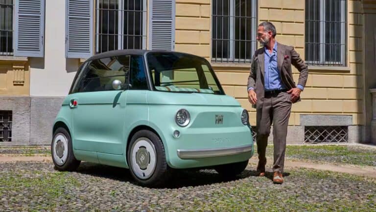 A stylish gentleman stands next to a Fiat Topolino