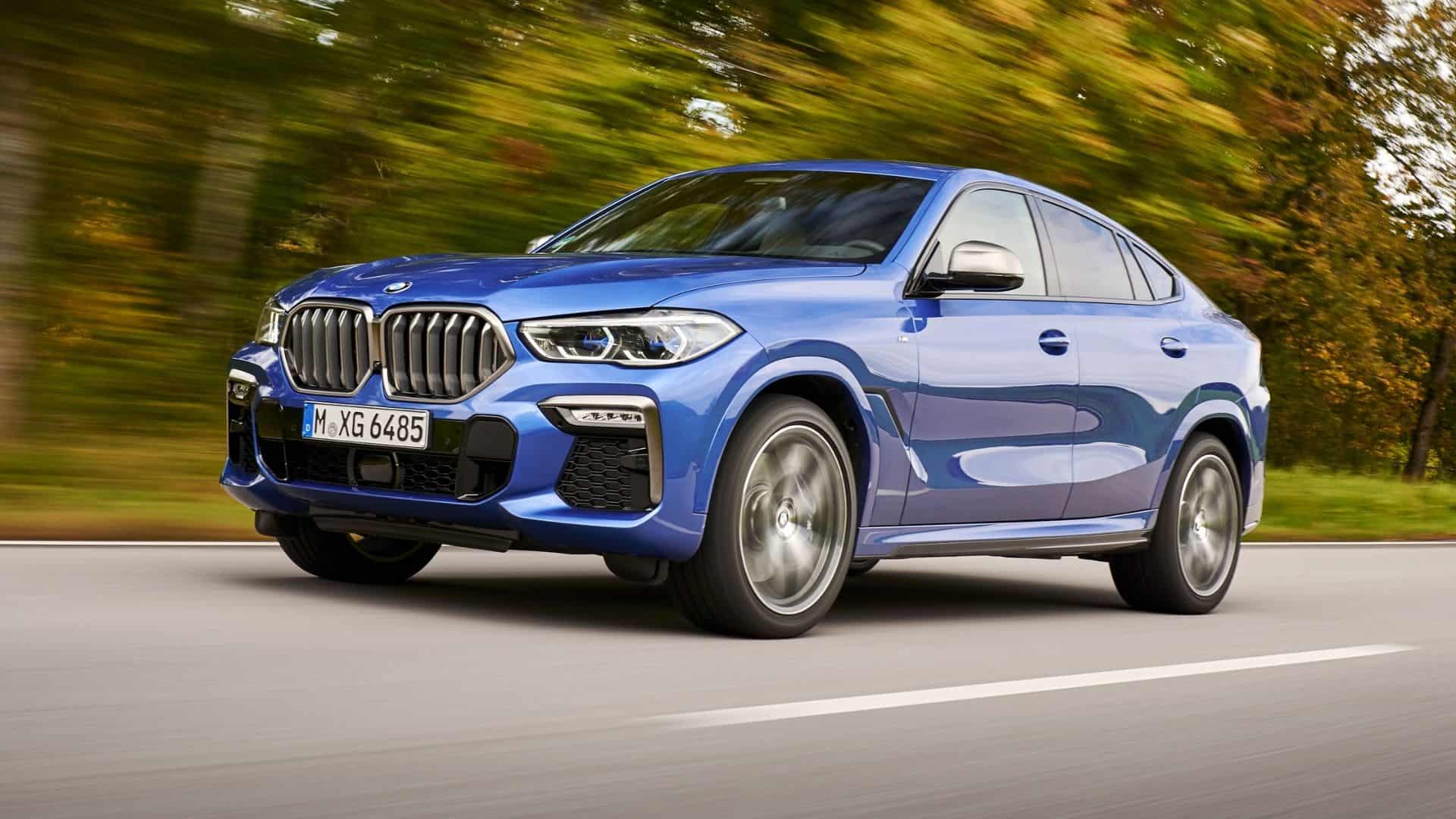A blue, 2026 BMW X6 driving down the road