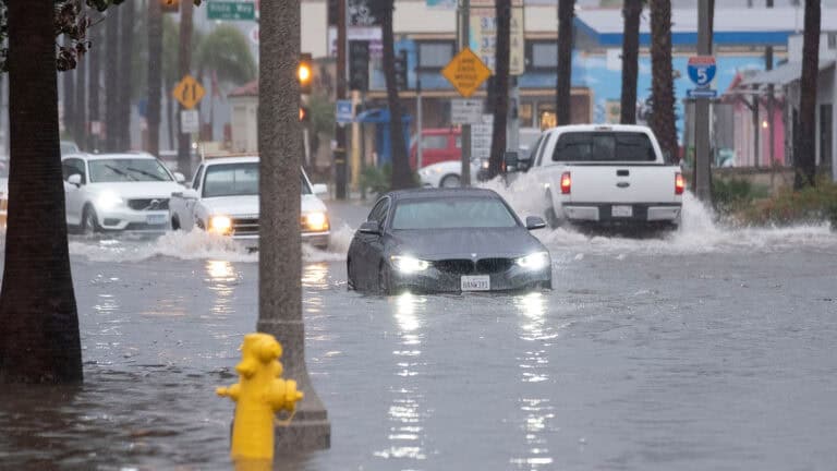 Car driving in water flooded street.