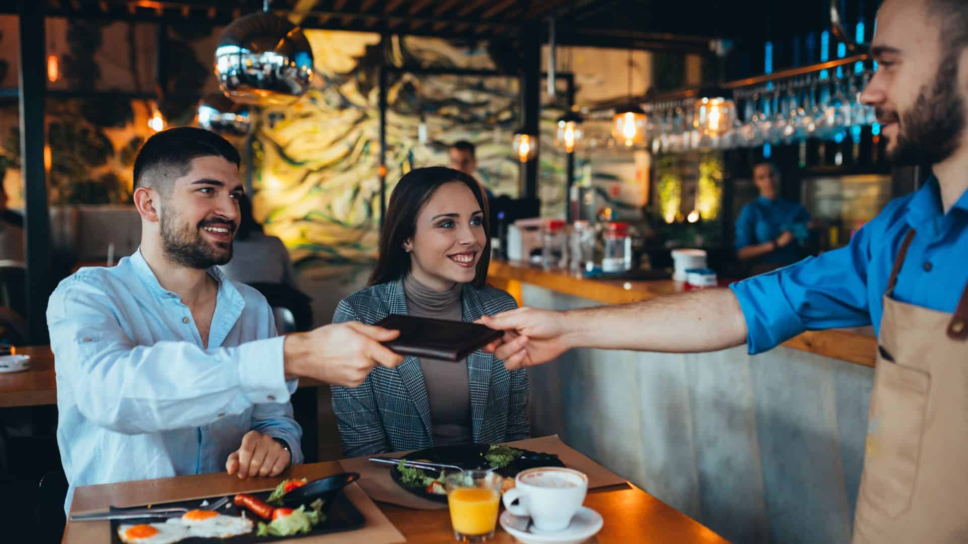 man paying bill with cash in restaurant