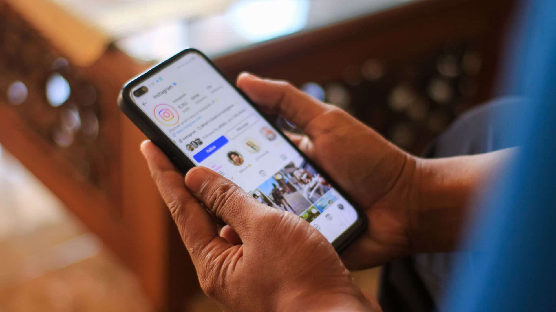 A man holds a smartphone with Instagram profile on the screen
