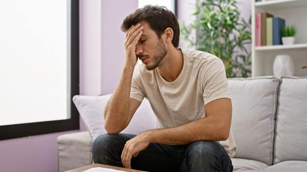 A worried man sitting on a couch indoors