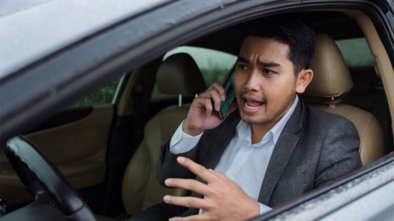A man in a car argues on the phone.