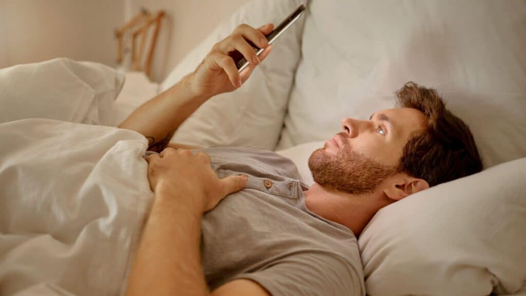 Man using phone in bed