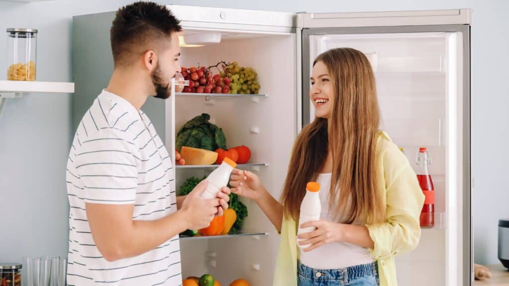 Young couple taking food out of fridge in kitchen