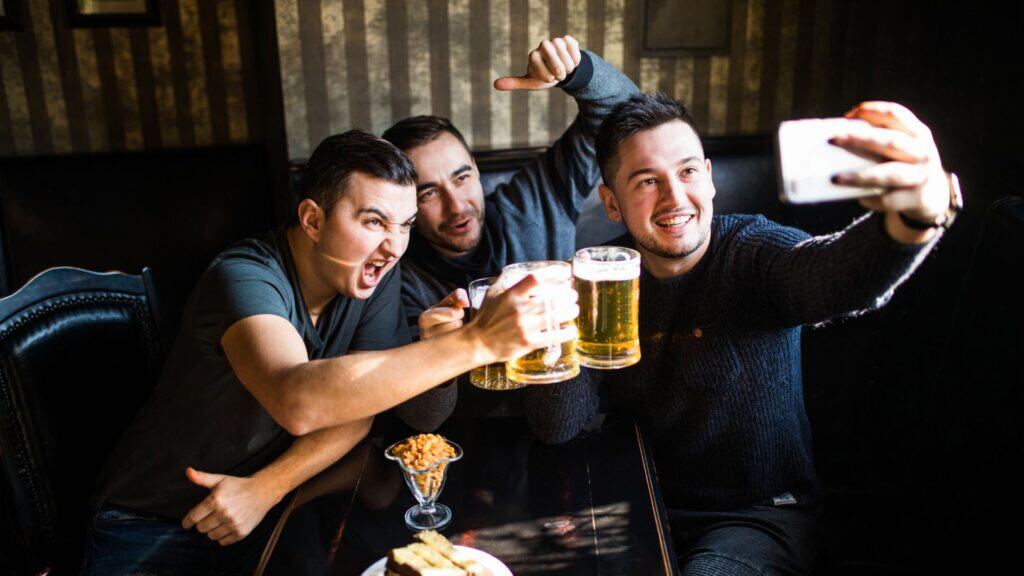 men taking selfie holding drinks