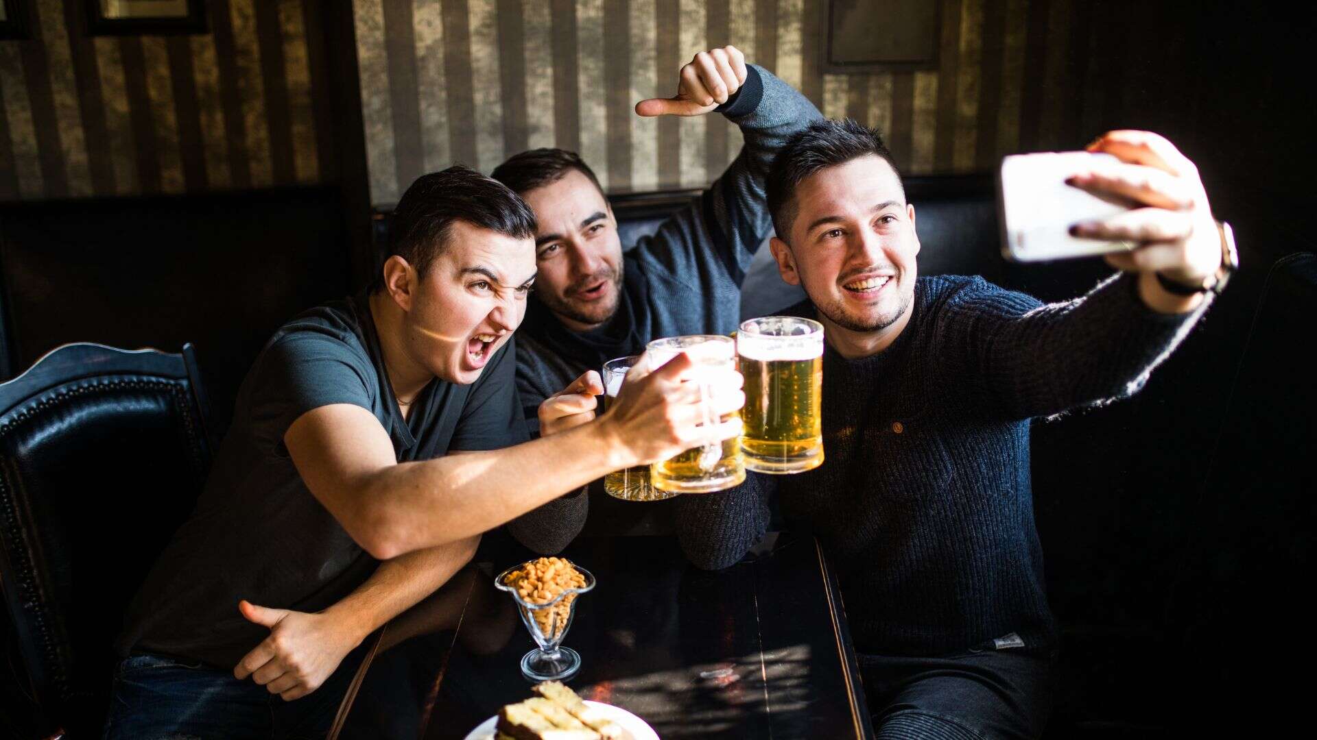 men taking selfie holding drinks
