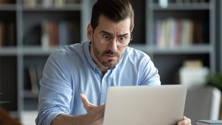 A frustrated man is checking his laptop.