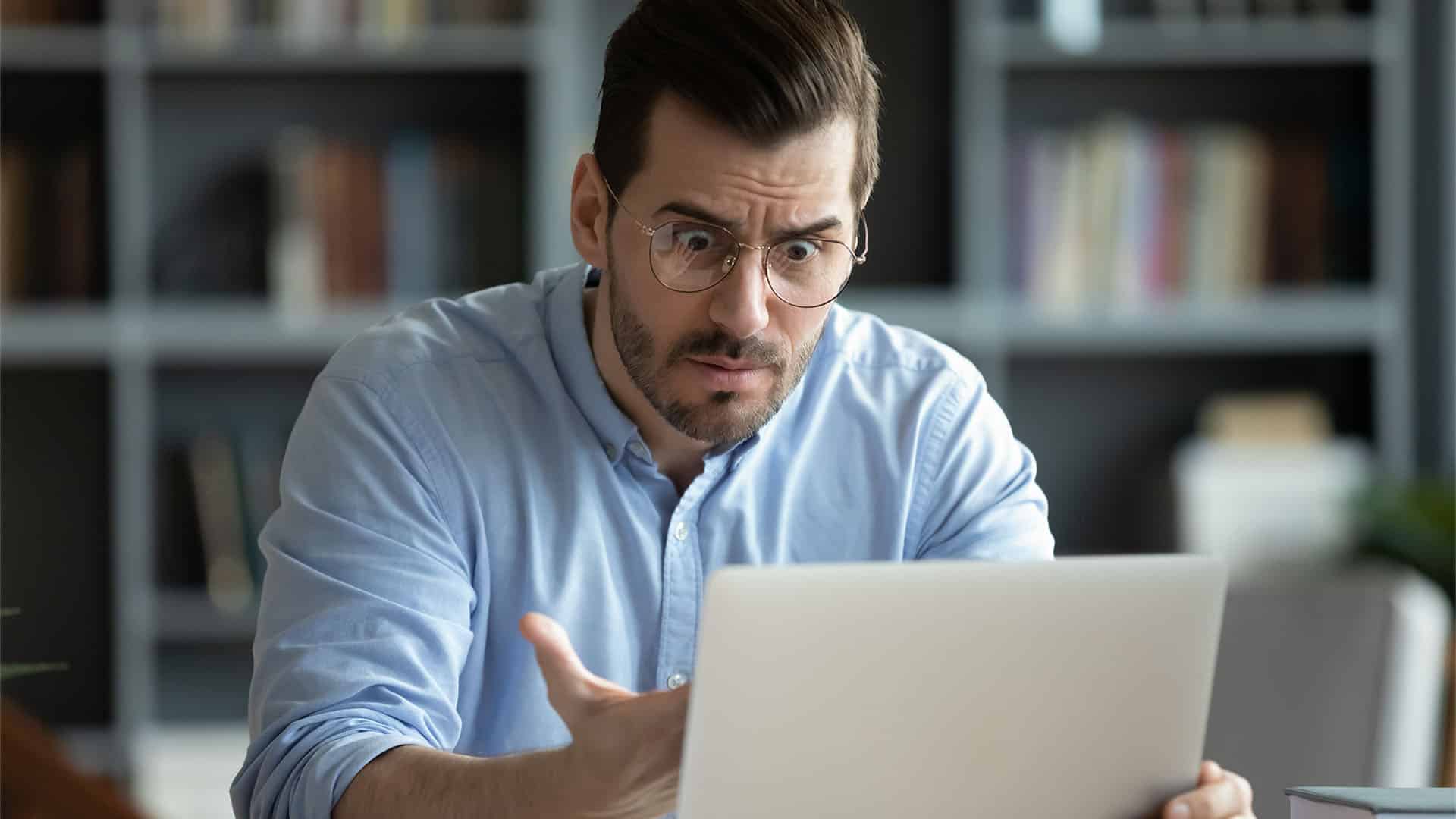 A frustrated man is checking his laptop.