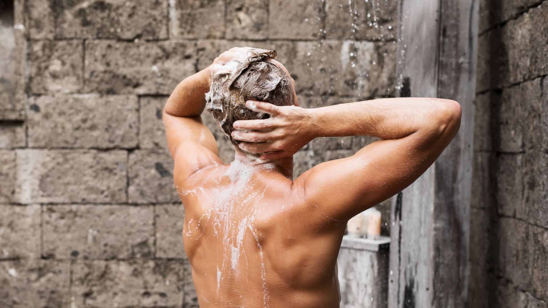 A man washing his hair while taking a shower