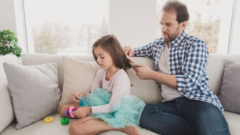 man brushes daughter's hair