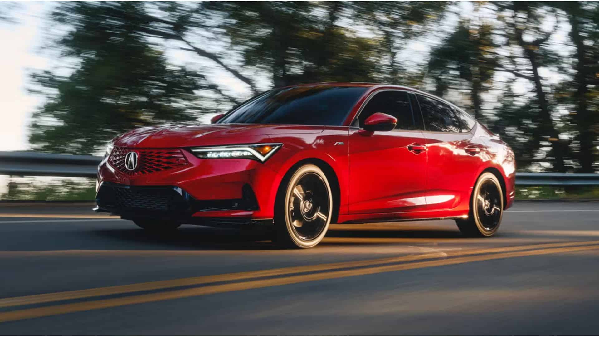 A red 2026 Acura Integra driving down a tree-lined road