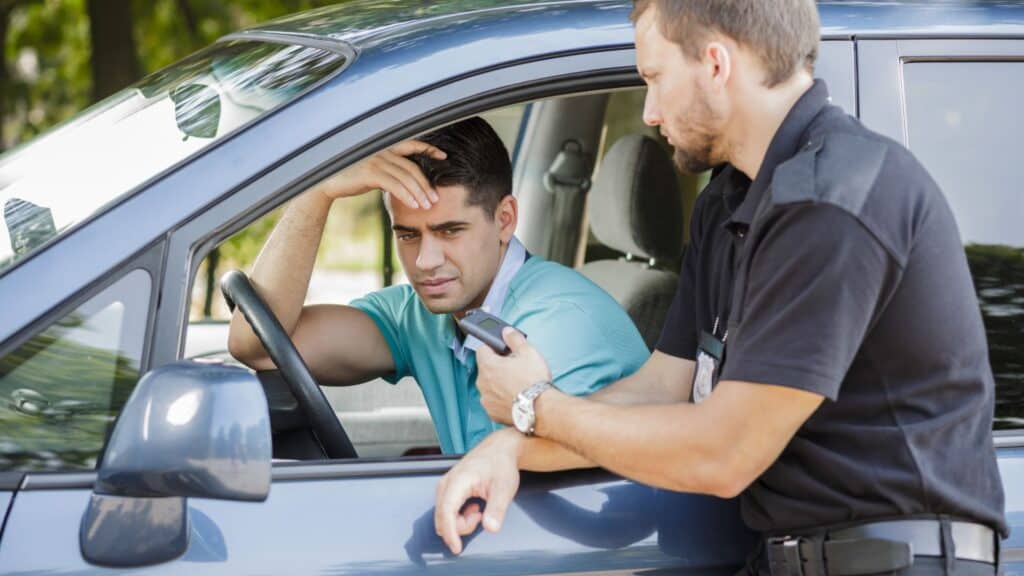 Police officer issuing speeding ticket to driver inside a car
