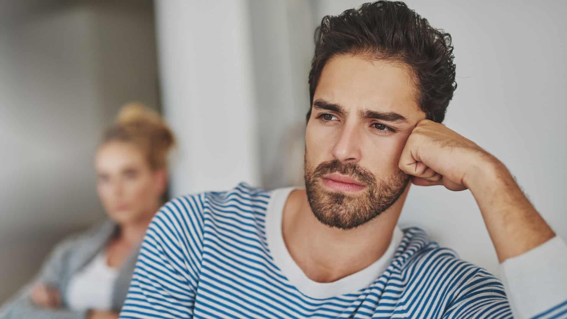 Young man with pensive expression, resting his head on his hand.