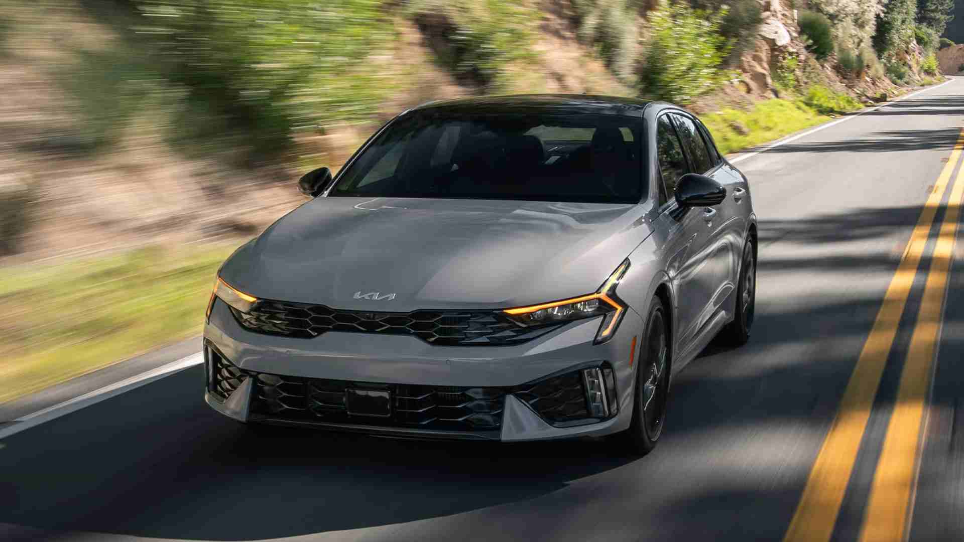 Grey, 2026 Kia K5 driving down a mountain road