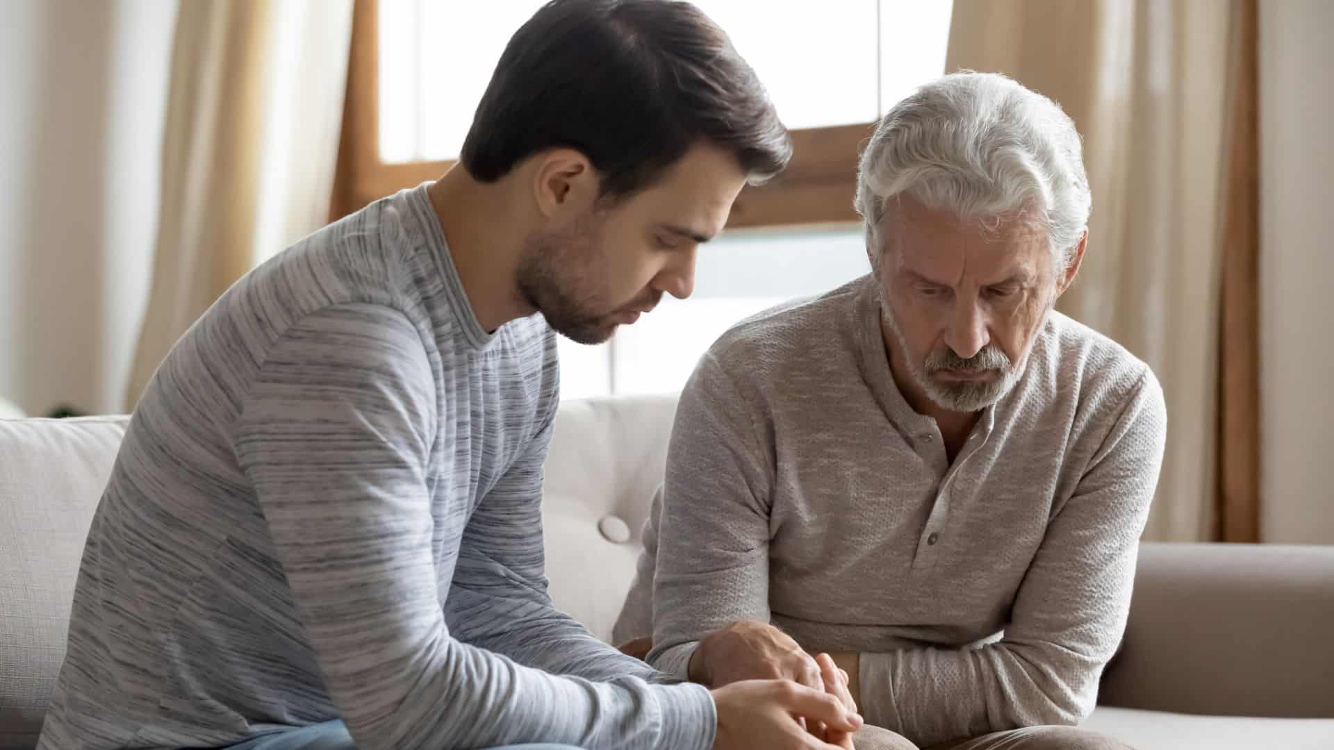 Worried grownup son supporting stressed older dad