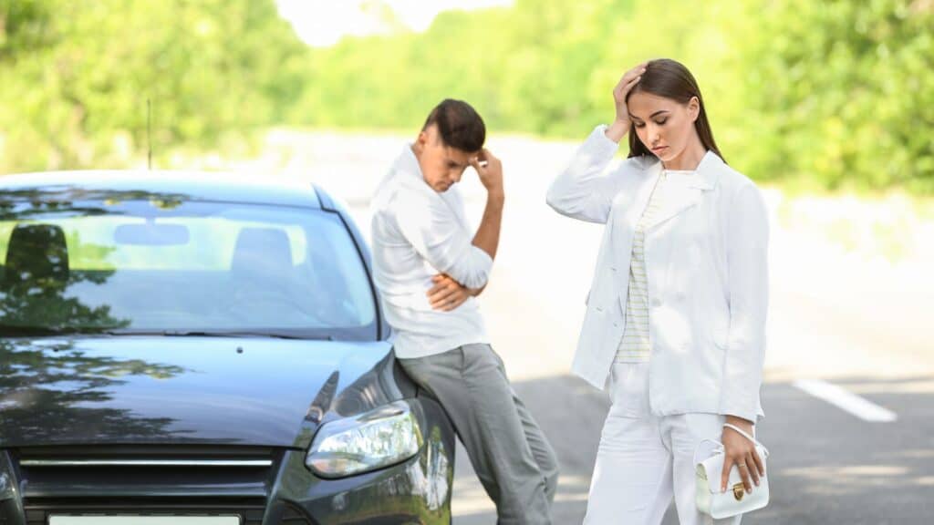 an upset couple standing near their car