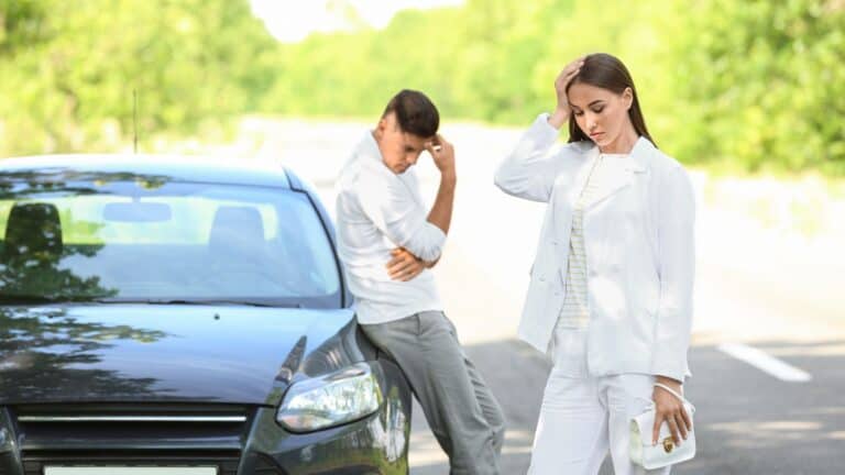 an upset couple standing near their car
