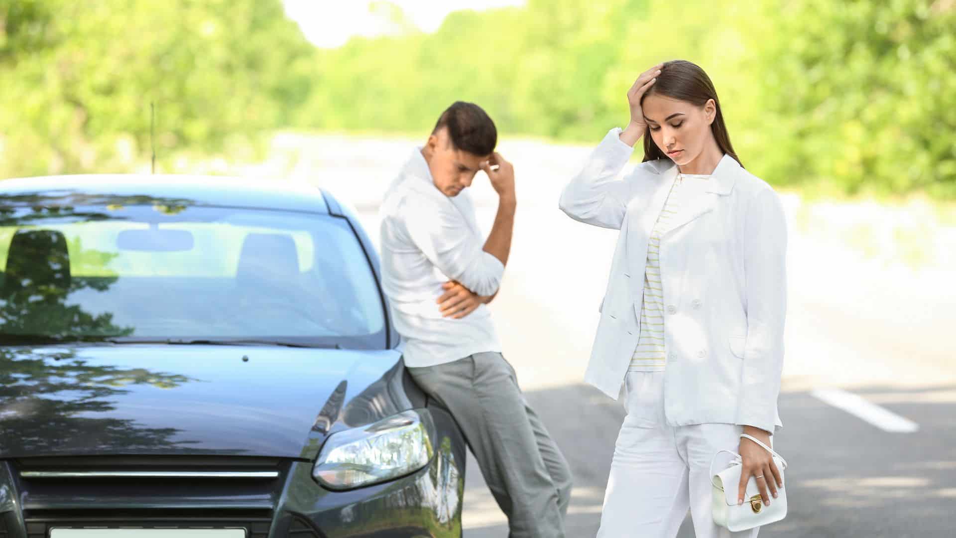 an upset couple standing near their car