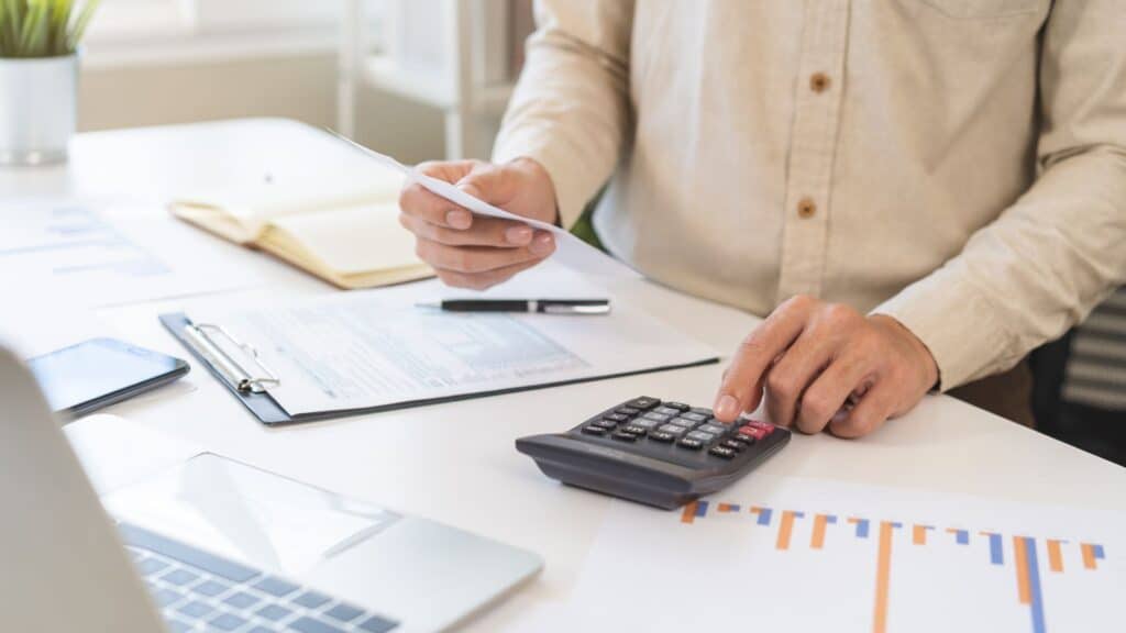 male using calculator to calculate expenses