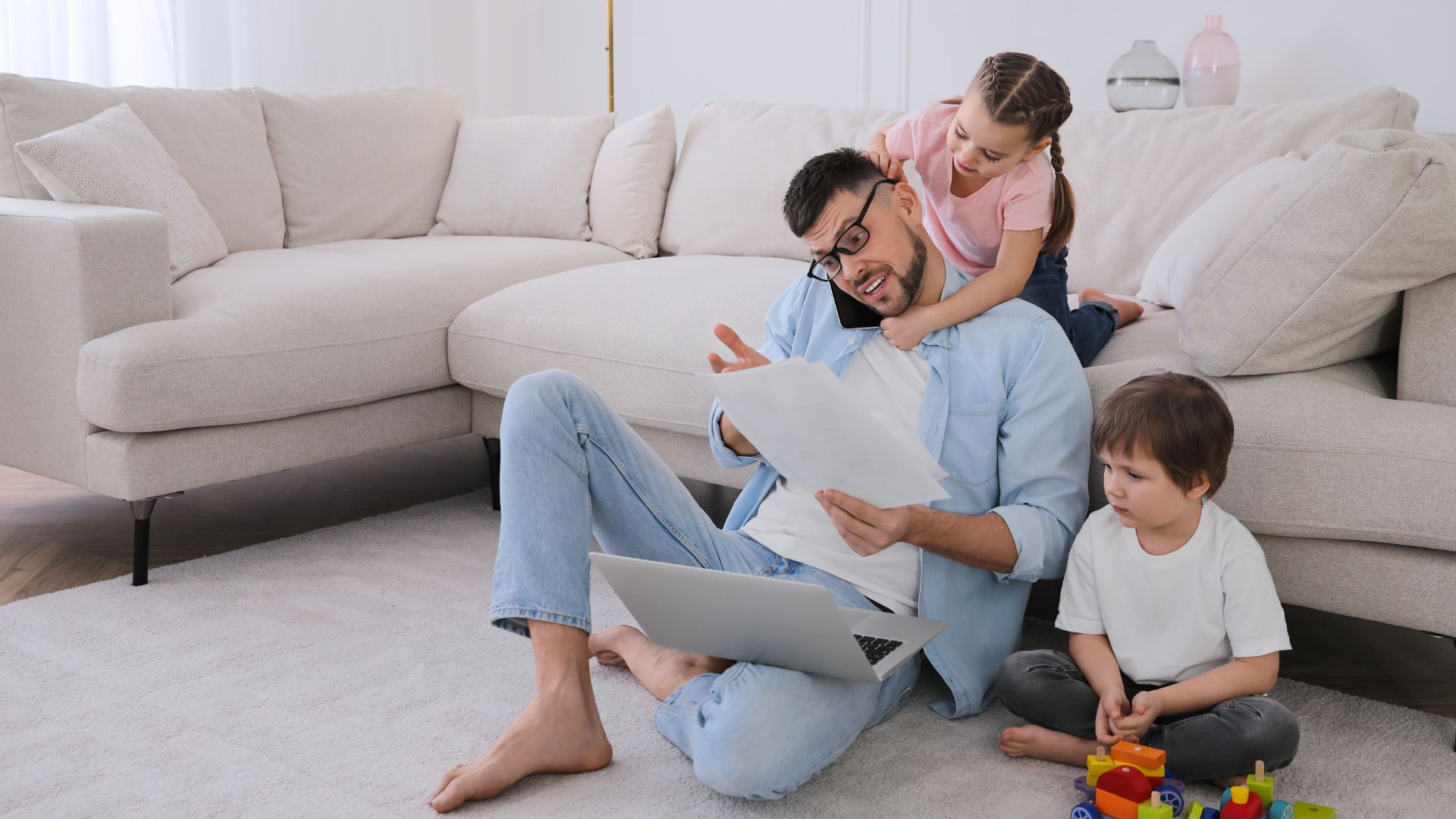 man on phone while his children are sitting around him