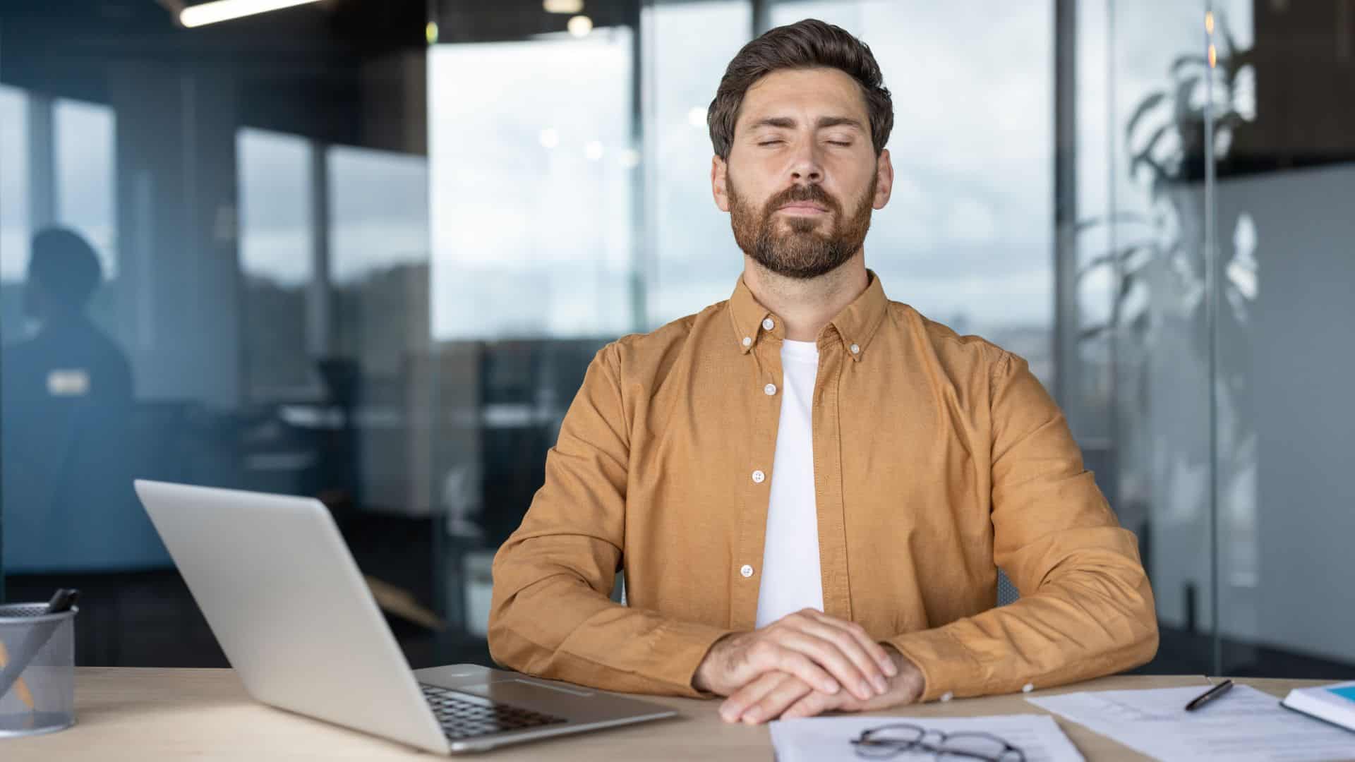 A relaxed businessman seated at his desk with eyes closed