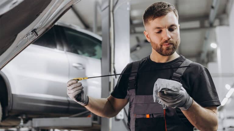Car mechanic checking oil level.