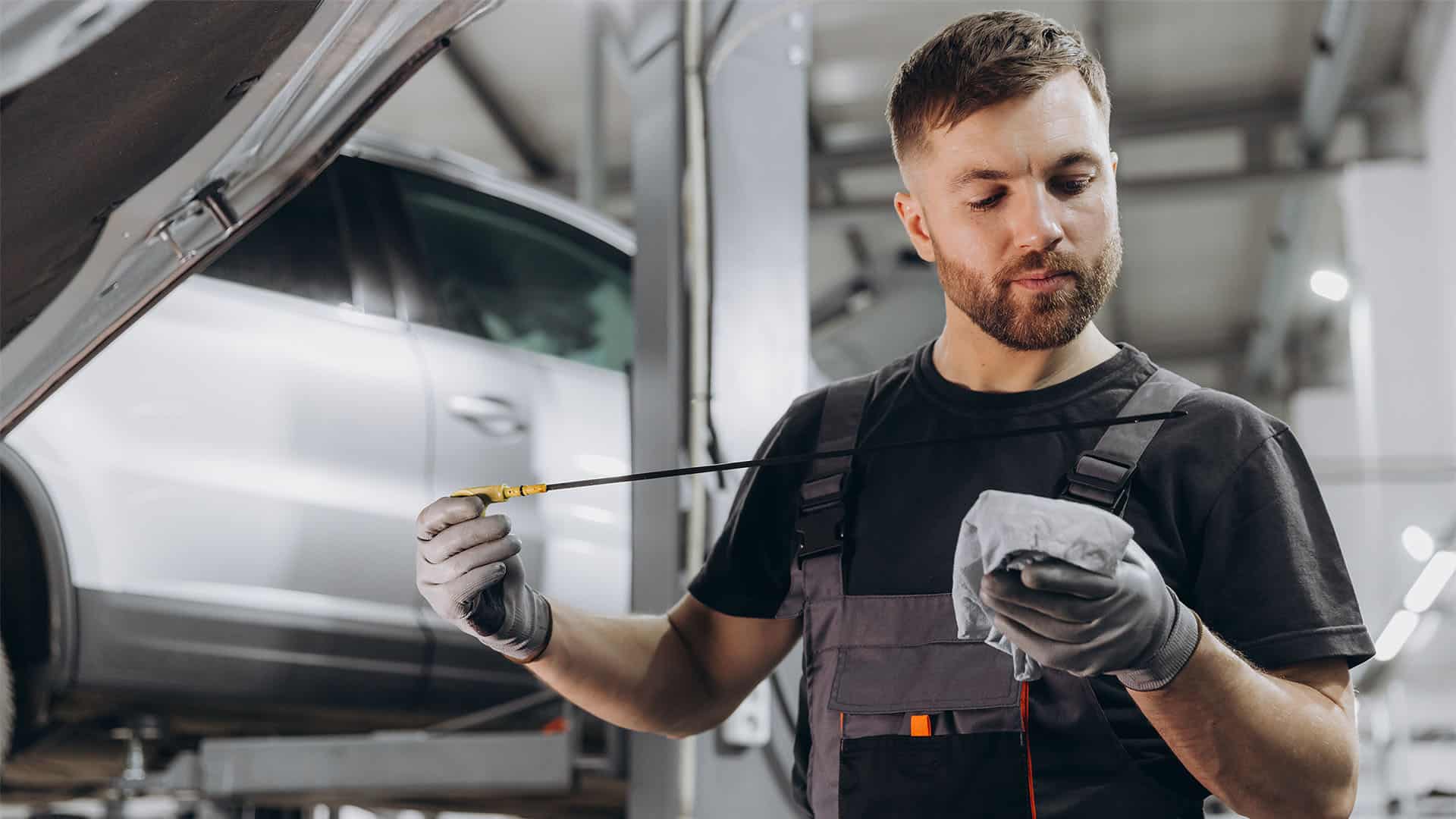 Car mechanic checking oil level.