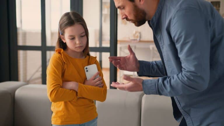 dad talking to his daughter who is holding mobile in her hand