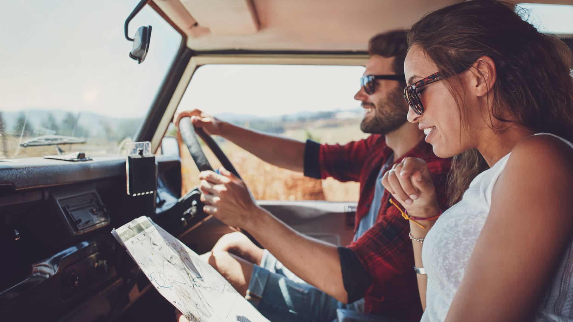 A woman reads a map while on a roadtrip with her husband