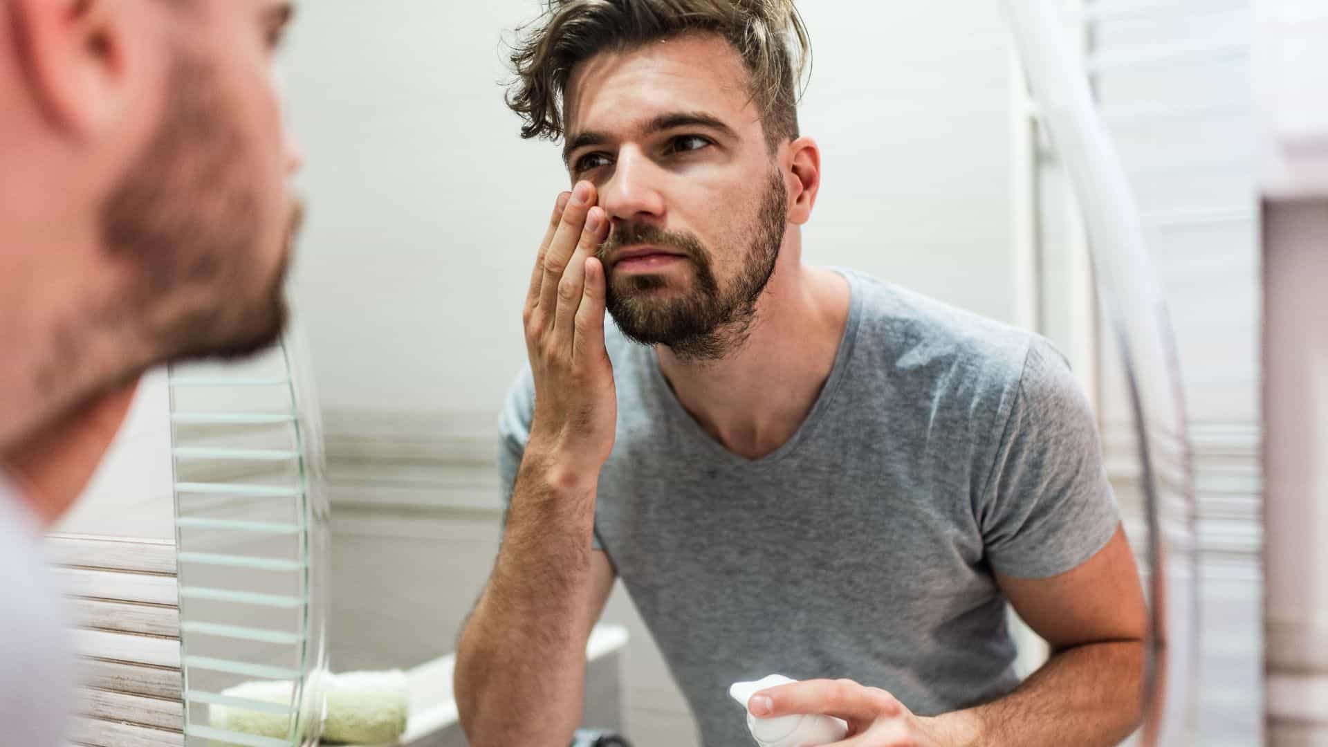 A man applying moisturizer in the mirror