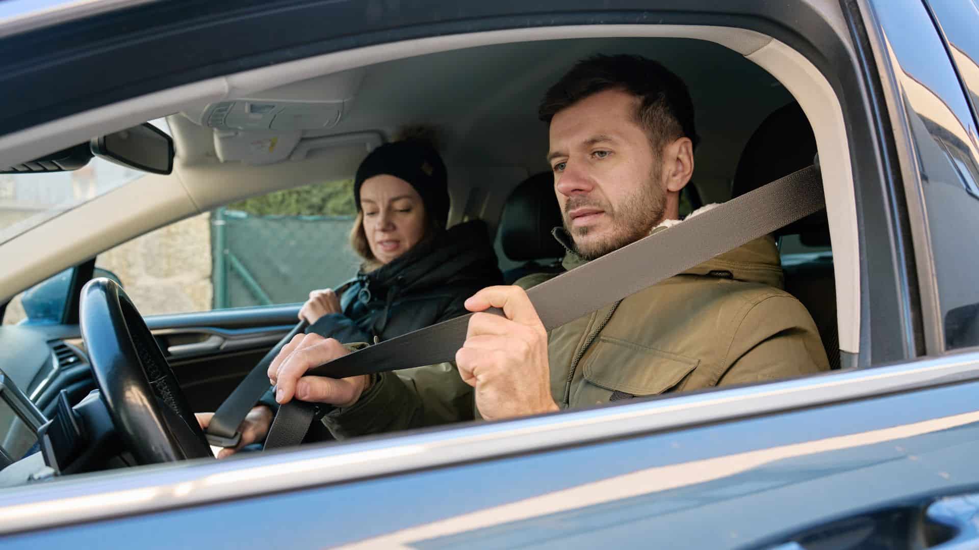 A man in the car adjusting his seatbelt