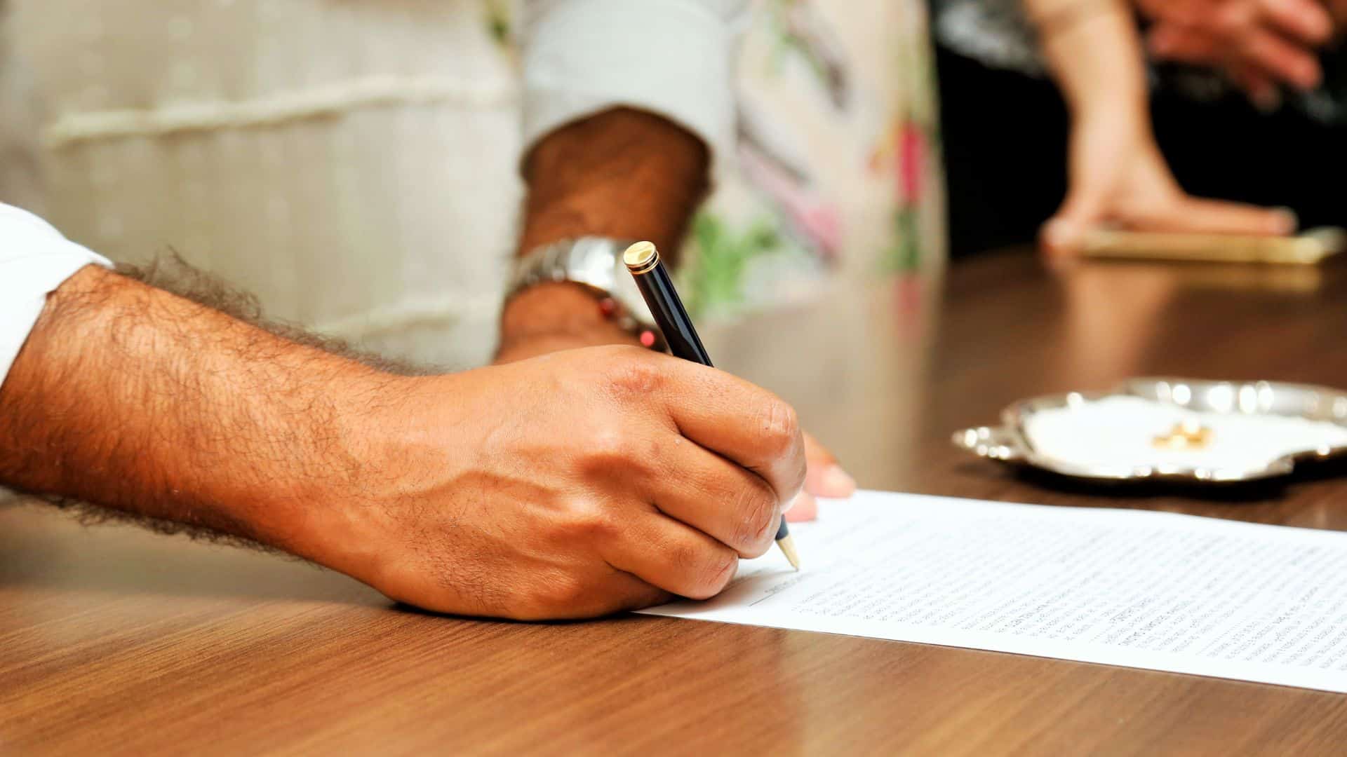 A man wearing a watch signing paperwork 