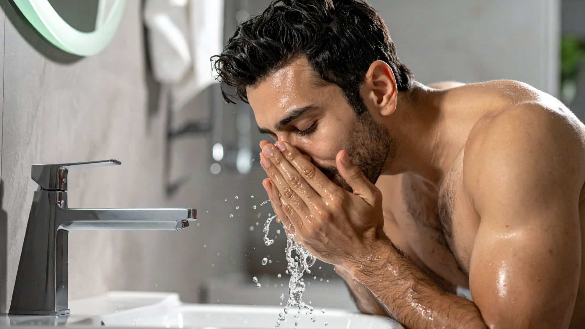 A man washing his face over the sink