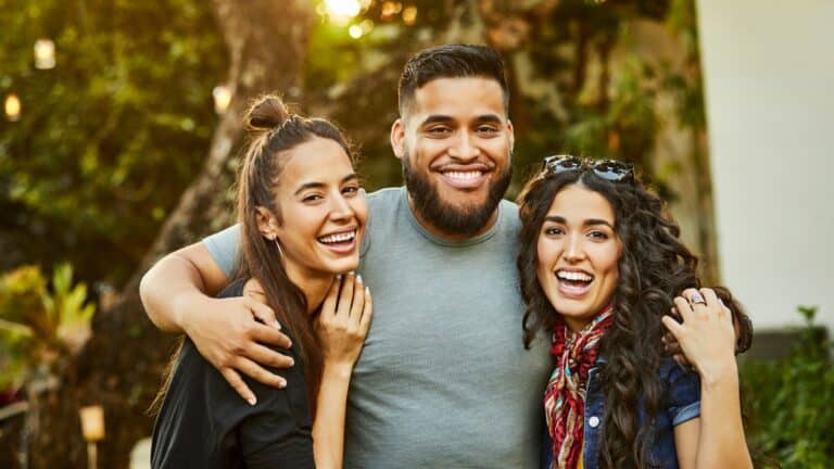 A man with his arms around his two female friends