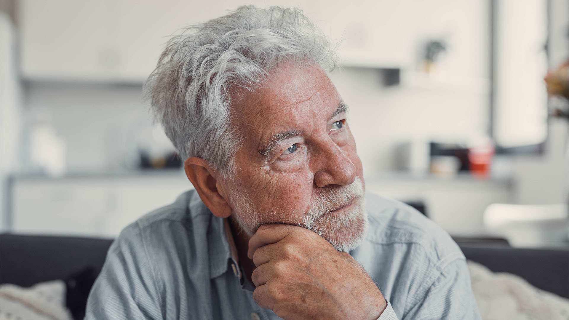 Sad old man sitting on a sofa.